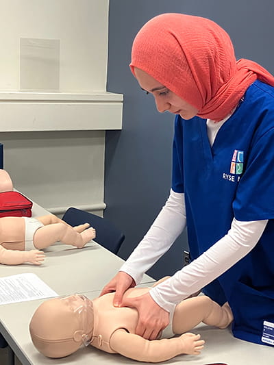 student simulating care for fake baby