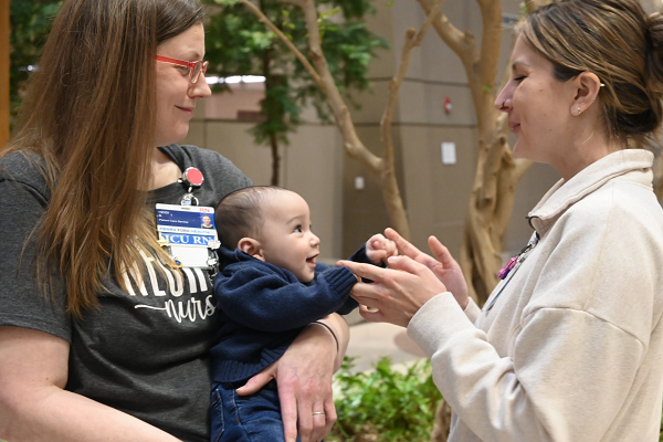 Heidi Serragaurd, RN ICU Educator at Henry Ford Health, holds Samuel Efrusy while Hannah Raynard, Henry Ford Health ICU RN, plays with him. Samuel and his mother Maris Efrusy were reunited with the care team that saved Maris' life following a amniotic fluid embolism shortly after childbirth. 